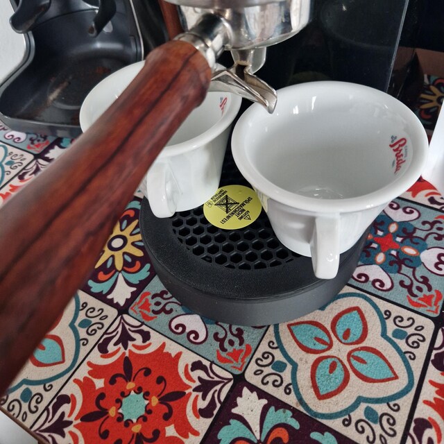 Magnetische Honeycomb-Abtropfschale an einer Dedica, zwei Espressotassen darauf, auf buntem Fliesentisch