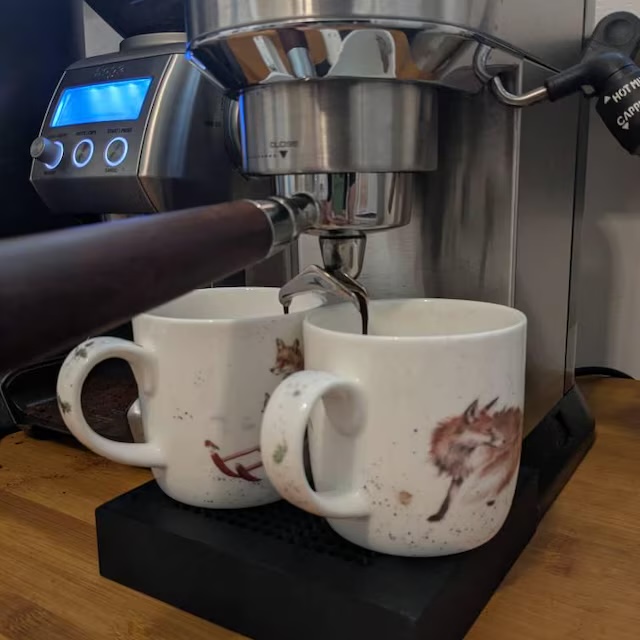 Zwei Tassen mit Fuchs-Motiv nebeneinander auf der Livanto-Abtropfschale, unter dem Siebträger einer De'Longhi Dedica